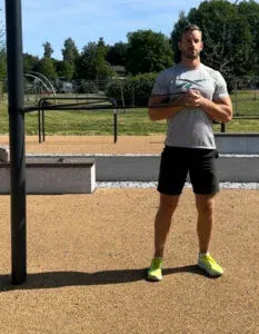 Mann trener utendørs med motstandsbånd, nøytralt uttrykk.